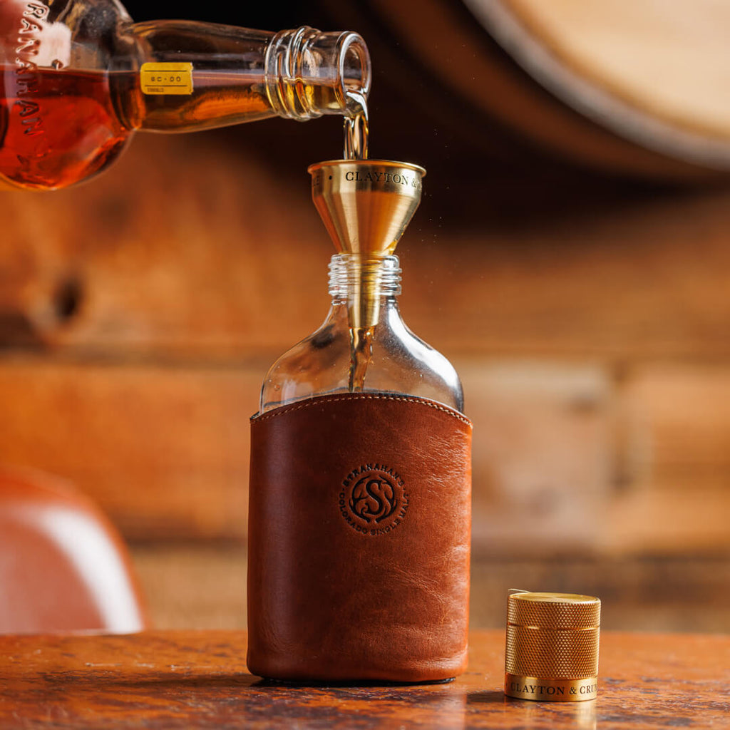 Stranahan's whiskey being poured into the funnel and into the Leather Glass Flask