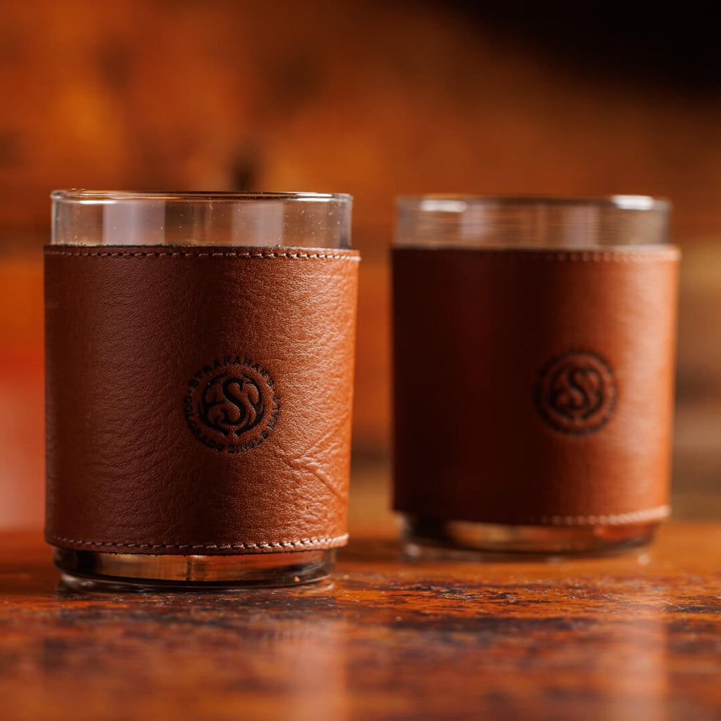 Two leather wrapped tumbler glasses stamped with the Stranahan's logo