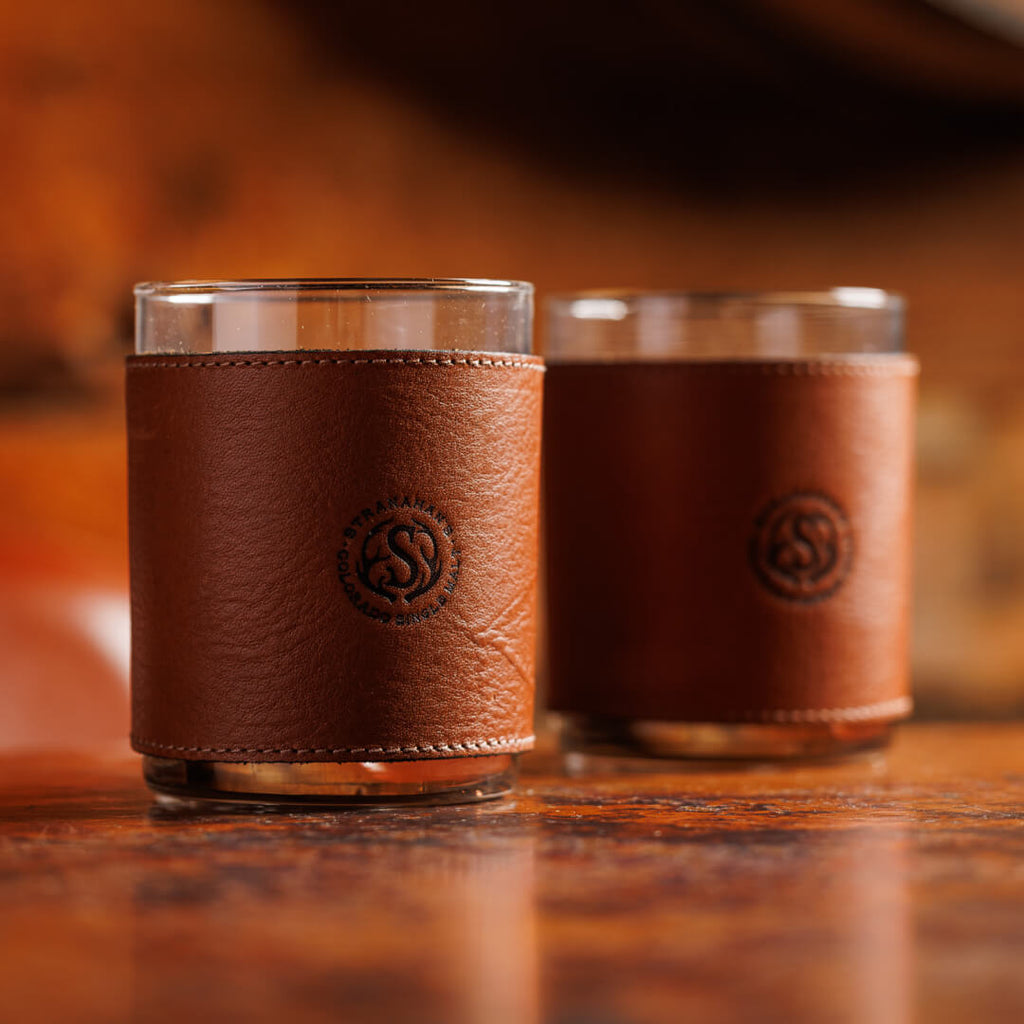 Two leather wrapped tumbler glasses stamped with the Stranahan's logo