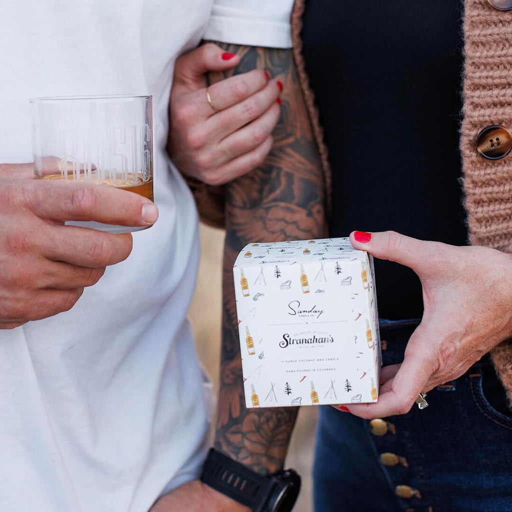 Stranahan's X Sunday Candle Co. Colorado Reserve Candle in amber glass vessel and hand-drawn packaging by artist Lauren Fuhr