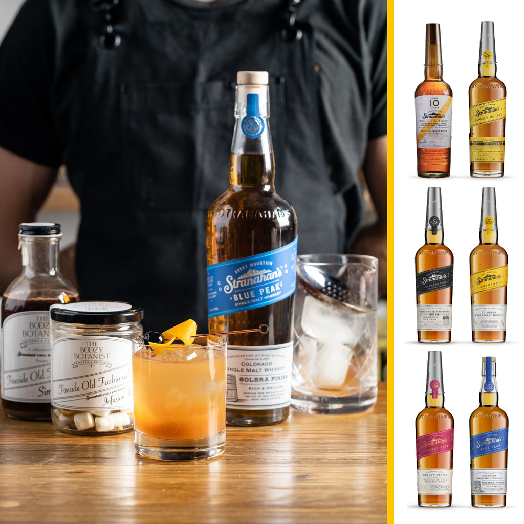 Stranahan's Blue Peaks whiskey bottle with a cocktail, and The Boozy Botanist's cocktail ingredients, next to a selection of Stranahan's whiskey bottles.