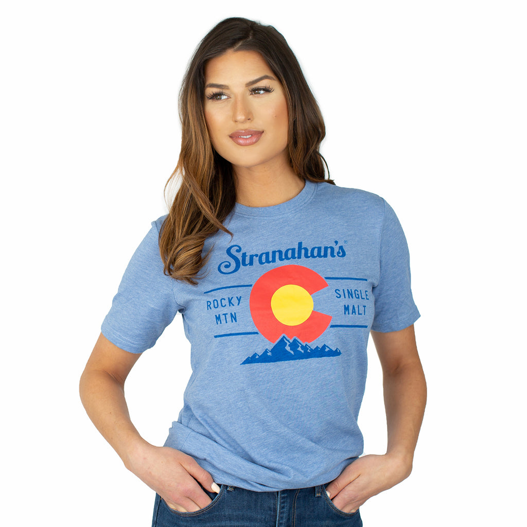 Front view of female model wearing light blue Stranahan's Colorado state flag tee.