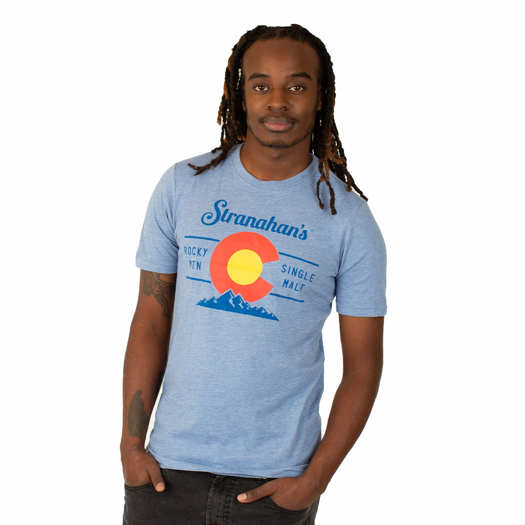 Front view of male model wearing light blue Stranahan's Colorado state flag tee.