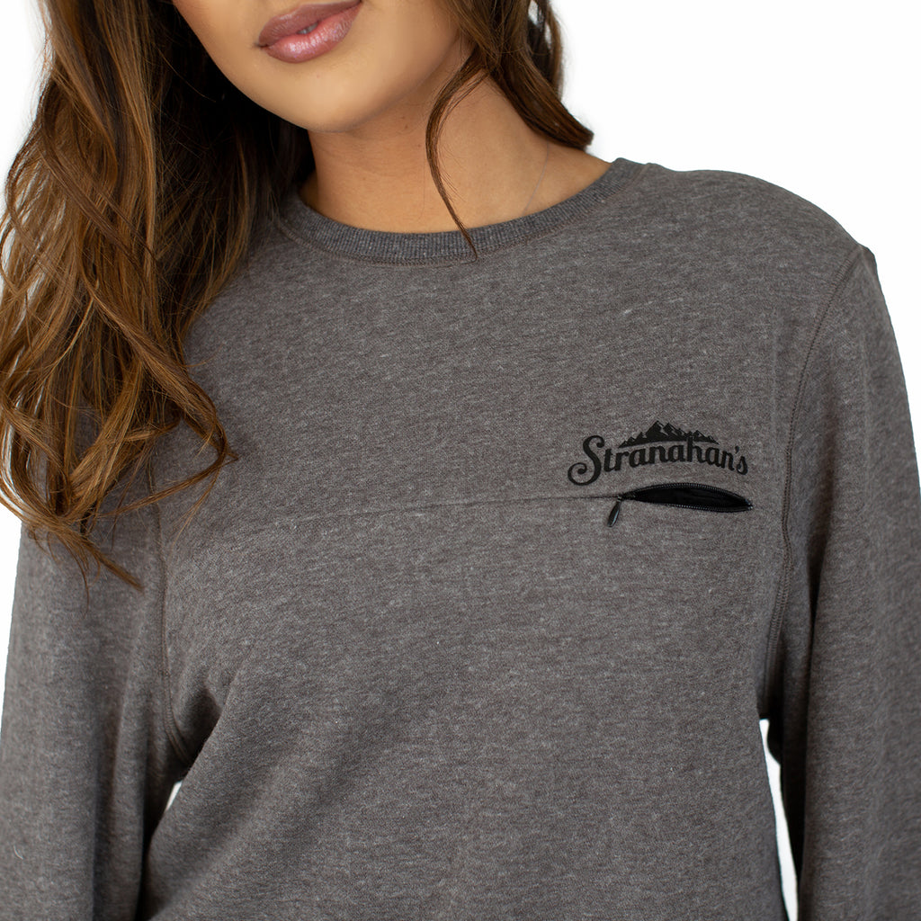 Close up of female model wearing grey crewneck pullover with black Stranahan's logo.