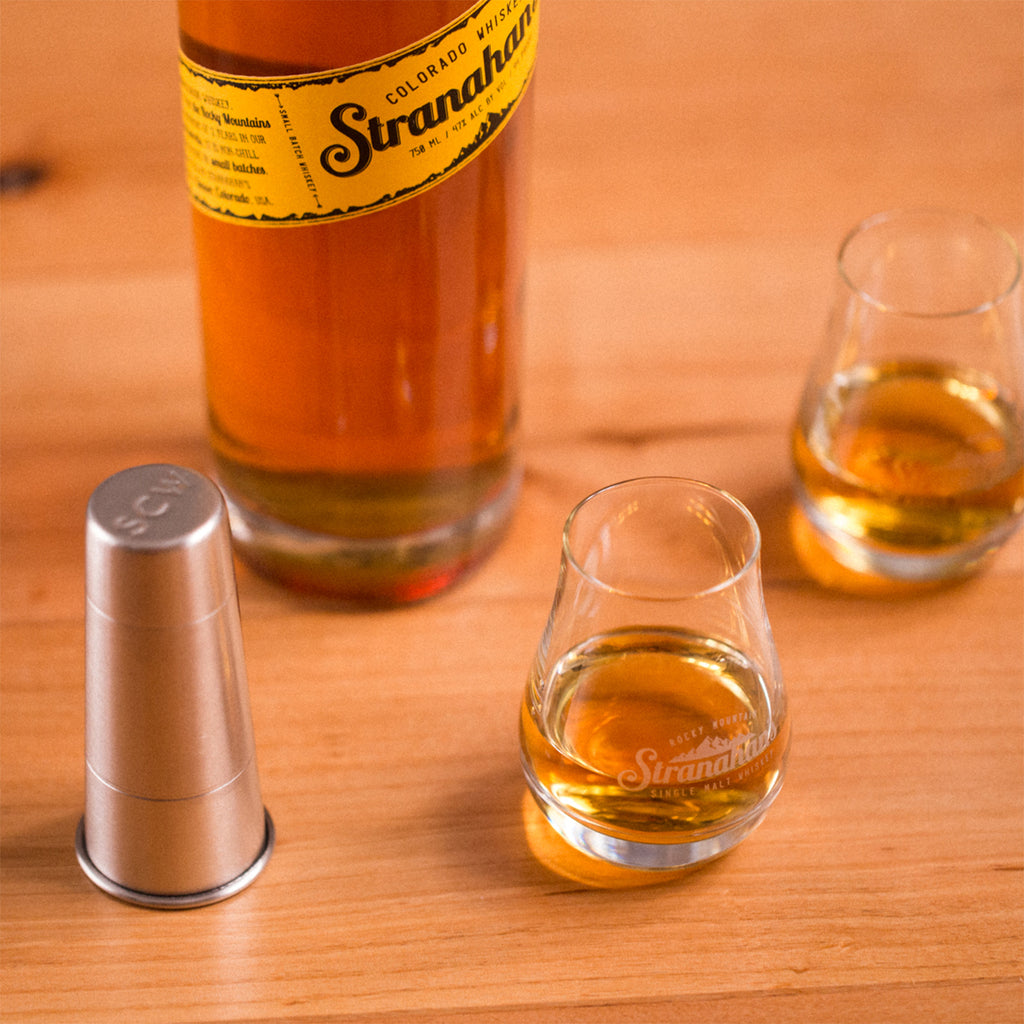 Nosing glasses filled with whiskey sitting next to bottle of Stranahan's Original whiskey.