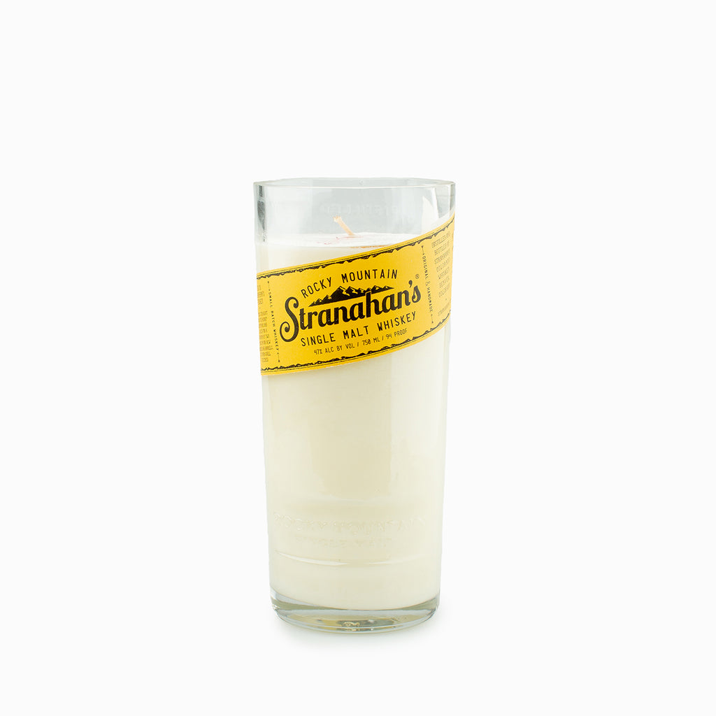 Tall white candle with Stranahan's Original whiskey label on white background.